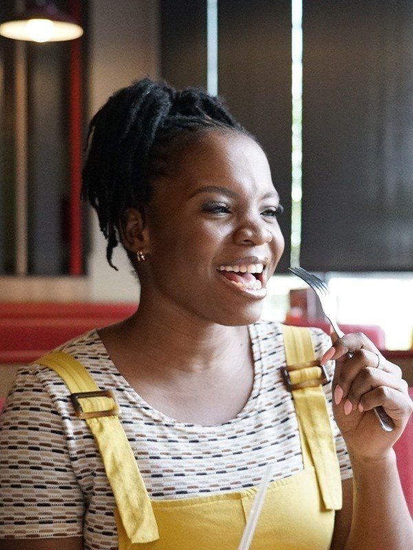 Smiling woman sitting at wimpy restaurant booth, holding a fork