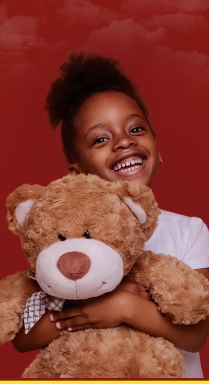 Smiling young girl holding a teddy bear against a red abstract background