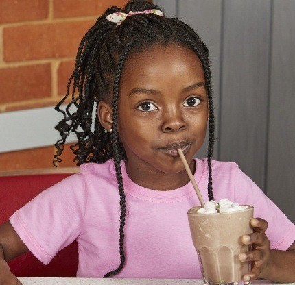 Young girl enjoying a chocolate milkshake in store
