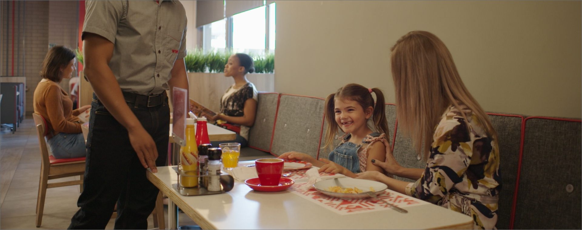 Waitron checking in on wimpy customers sitting at a table