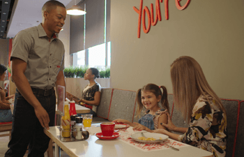 Waitron checking in on wimpy customers sitting at a table