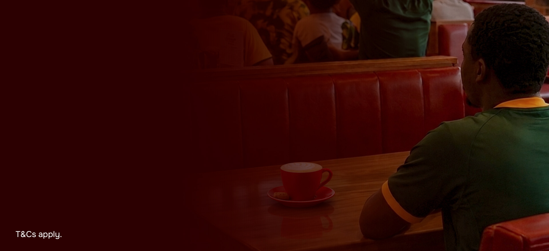 Man sitting at a table with a cup of coffee wearing a springbok shirt